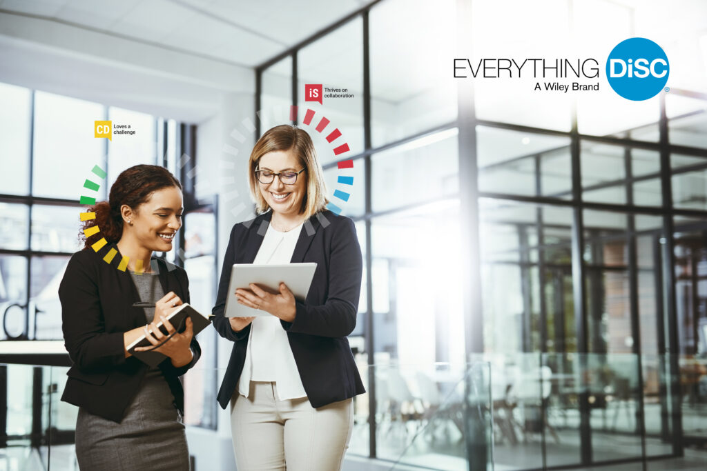 Image shows two women smiling while looking at a tablet with the DiSC insight halo around them.
