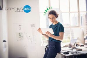 Image shows a woman holding a tablet with the Everything DiSC logo