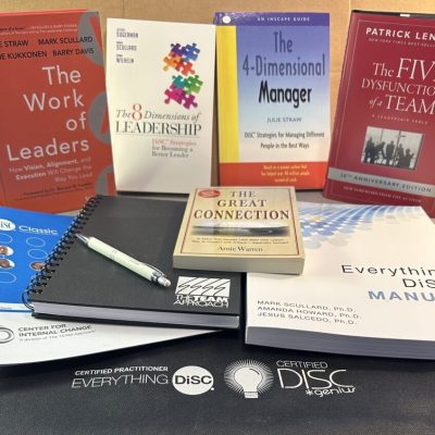 Image shows four books (Work of Leaders, Four Dimensional Manage, 8 Dimensions of Leadership, and Five Dysnfunctions of a team behind a DiSC Classic paper profile, notebook, the book The Great Connection, and the Everything DiSC manual.